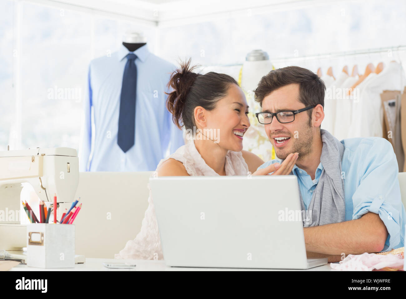 Male and female fashion designers using laptop at work in a studio ...
