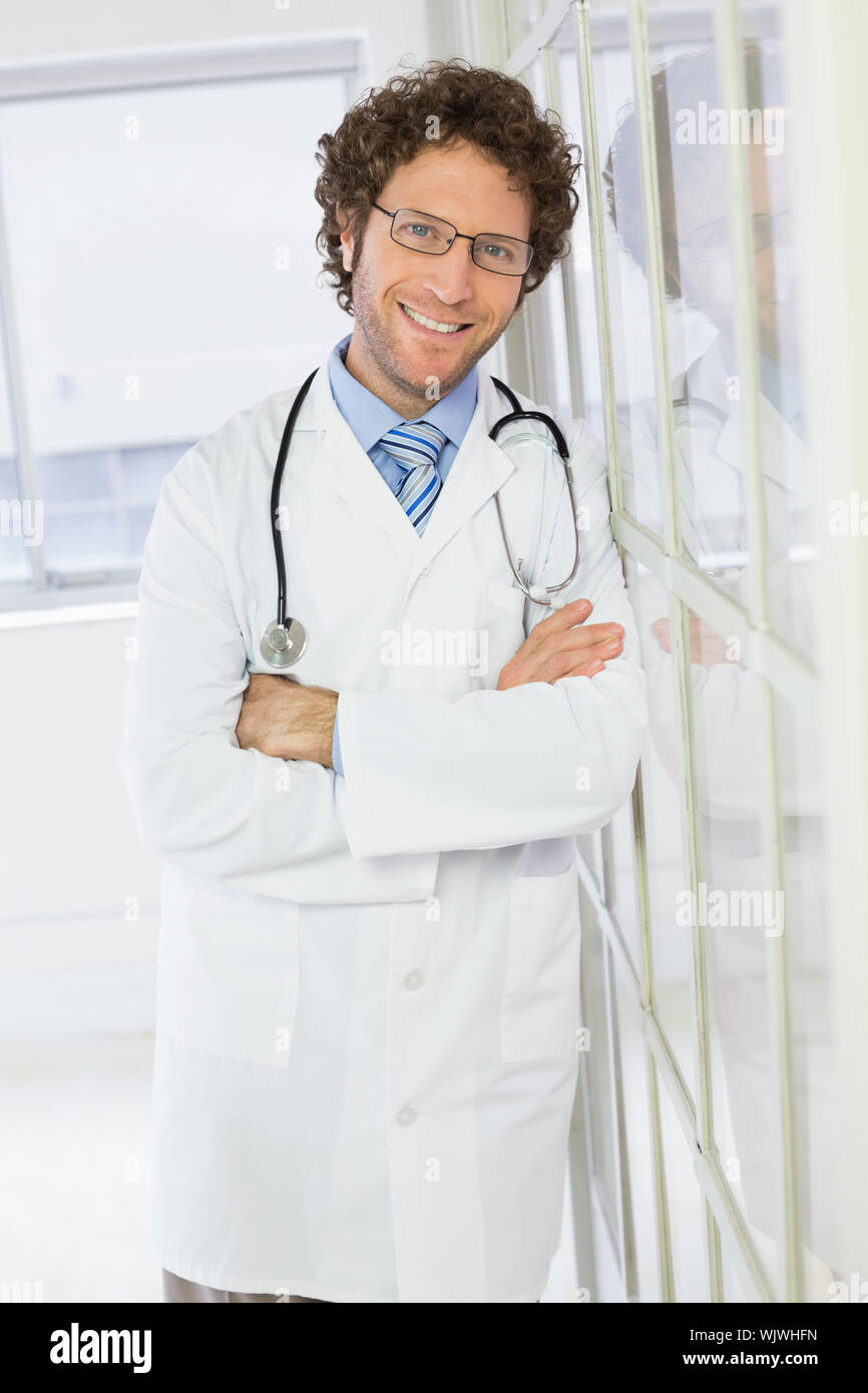 Portrait of a happy handsome male doctor standing with arms crossed in ...