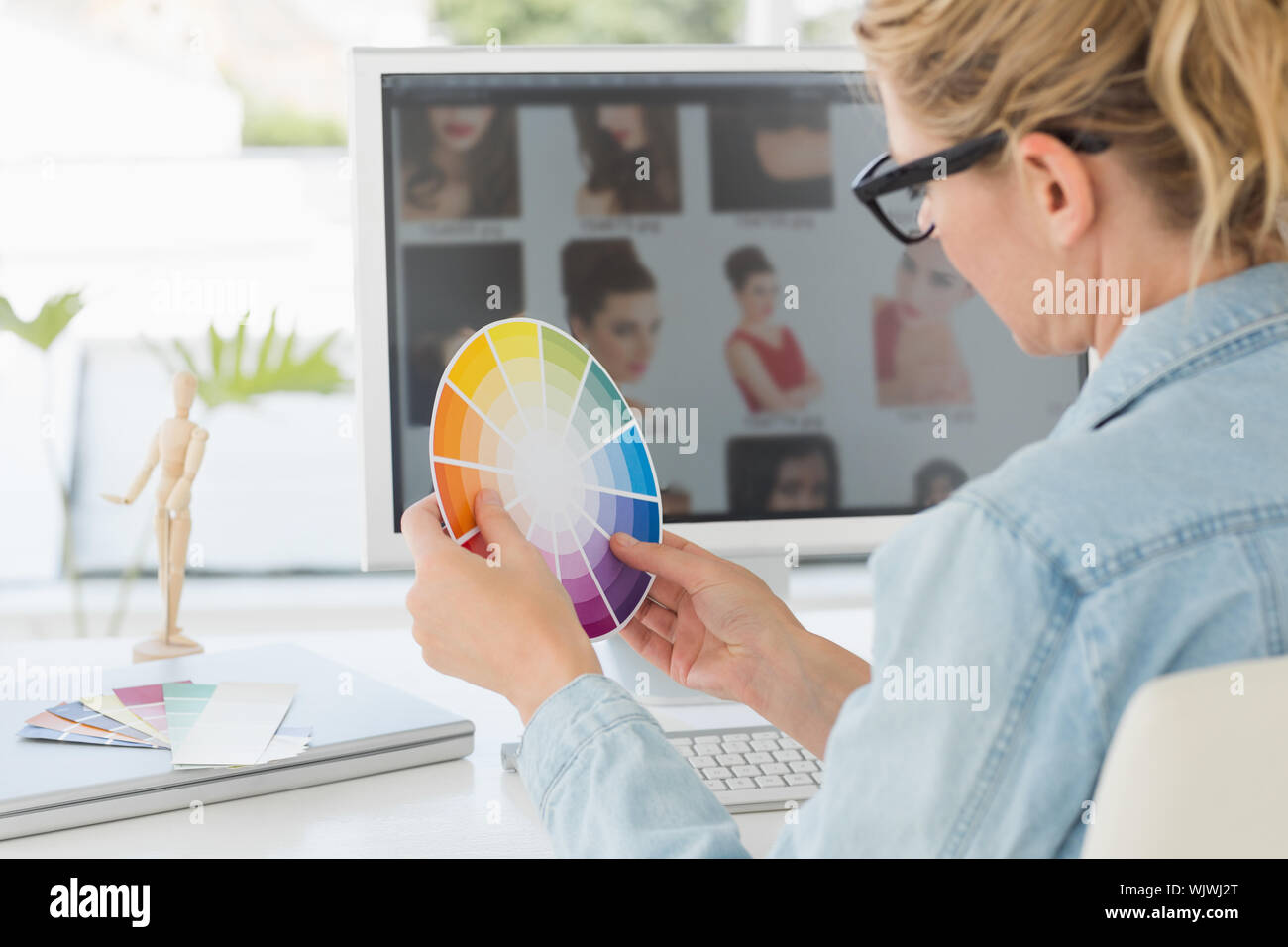 Blonde focused designer working at her desk holding a colour wheel in creative office Stock Photo