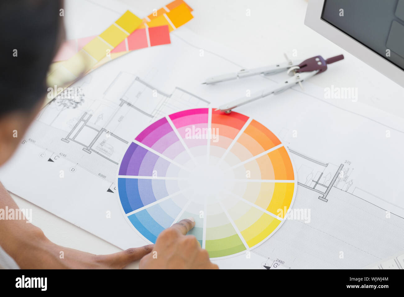 Interior designer looking at colour wheel at desk in creative office Stock Photo