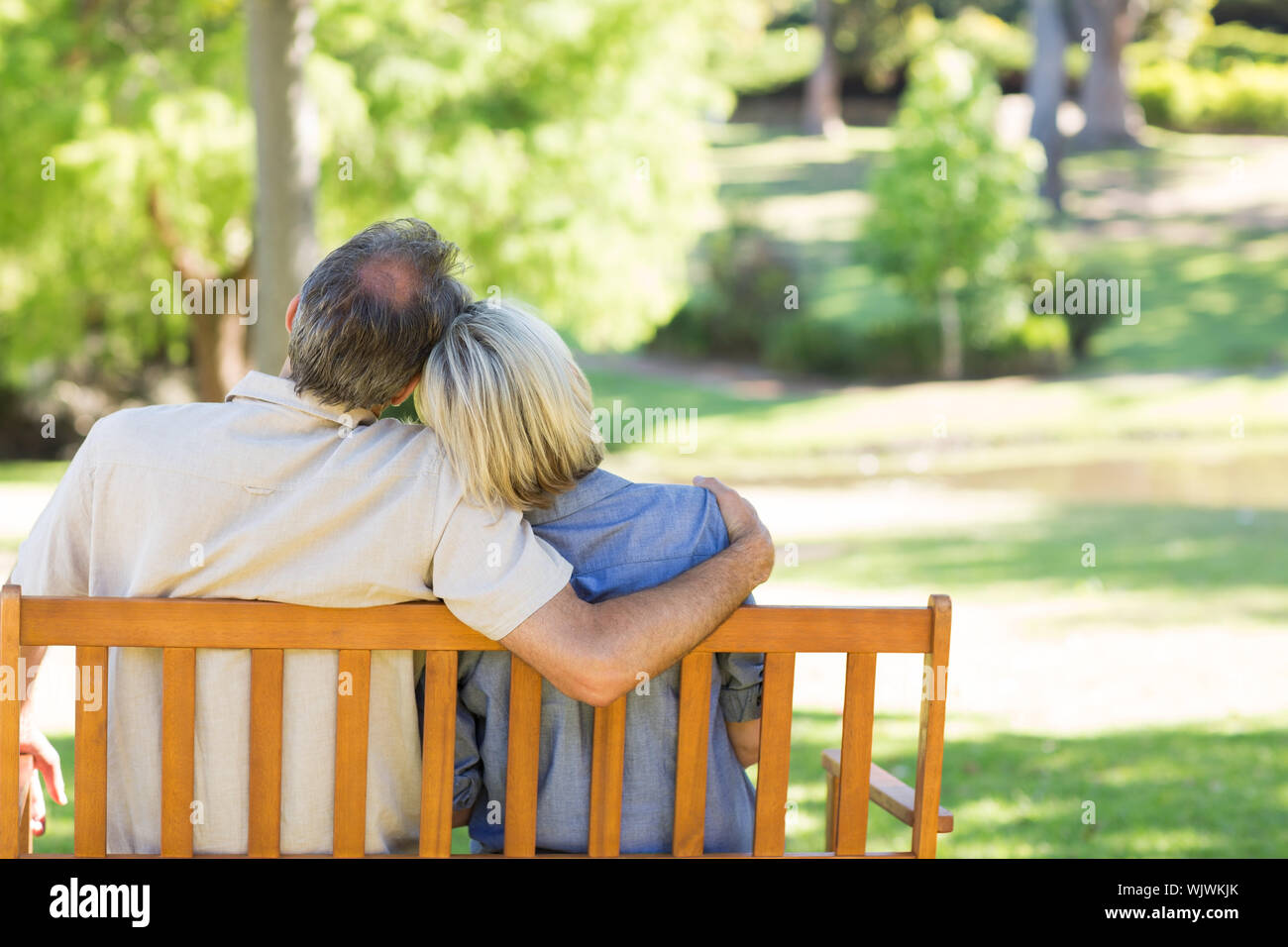 Rear view of loving couple relaxing on park bench Stock Photo - Alamy