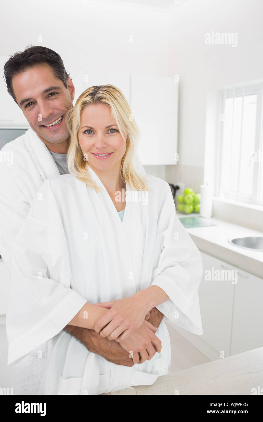Portrait of a man embracing woman from behind in the kitchen at home ...