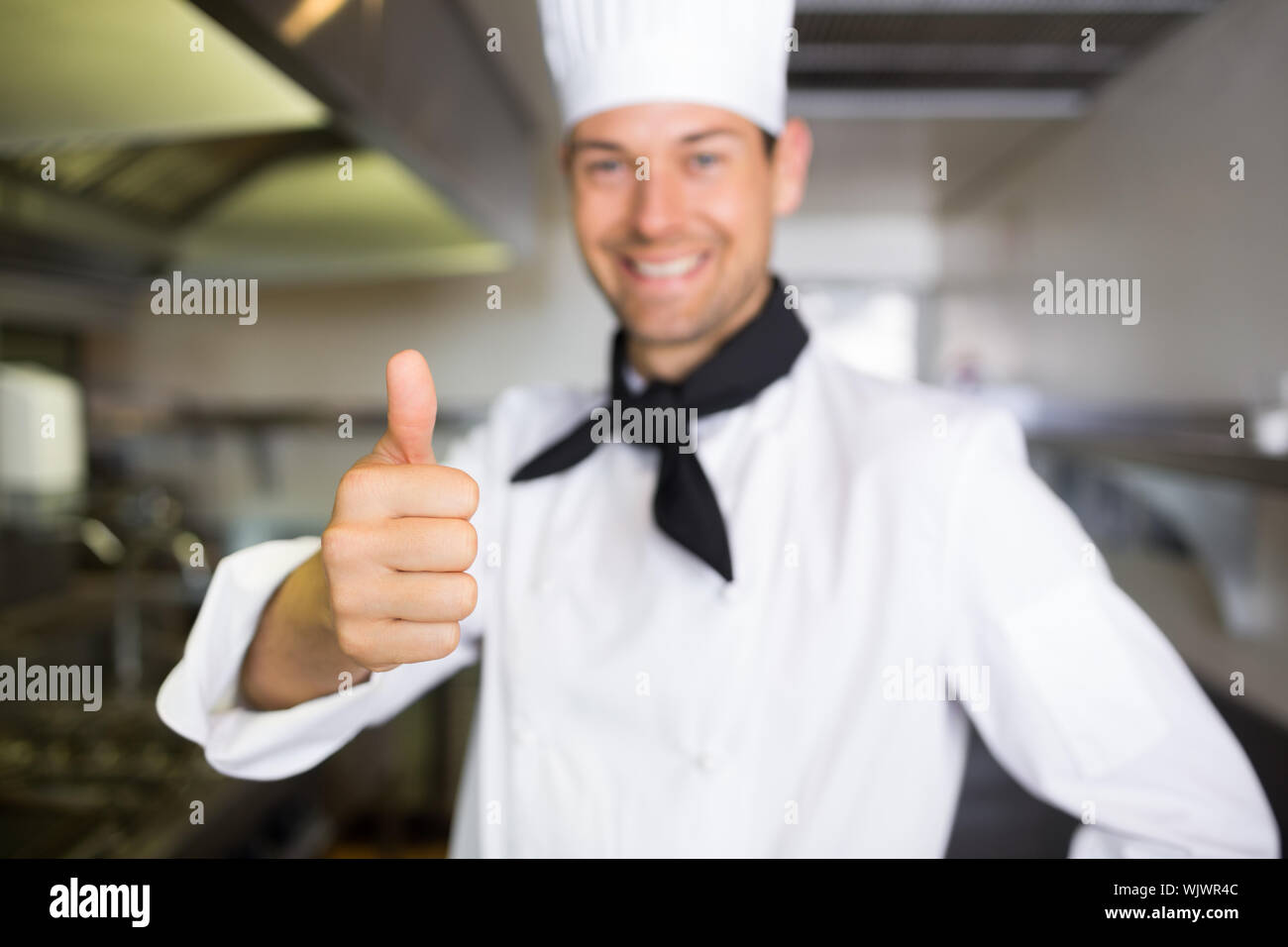 Portrait of a smiling male cook gesturing thumbs up in the kitchen ...