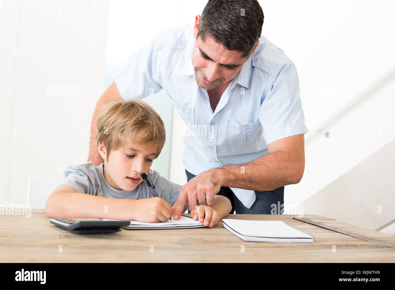 Father assisting son in doing homework at home Stock Photo