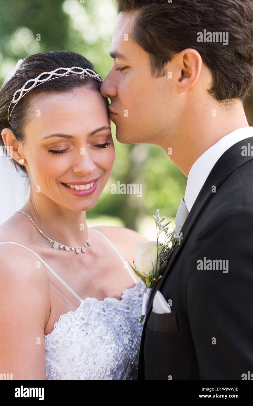 Young groom kissing beautiful bride on head in garden Stock Photo - Alamy