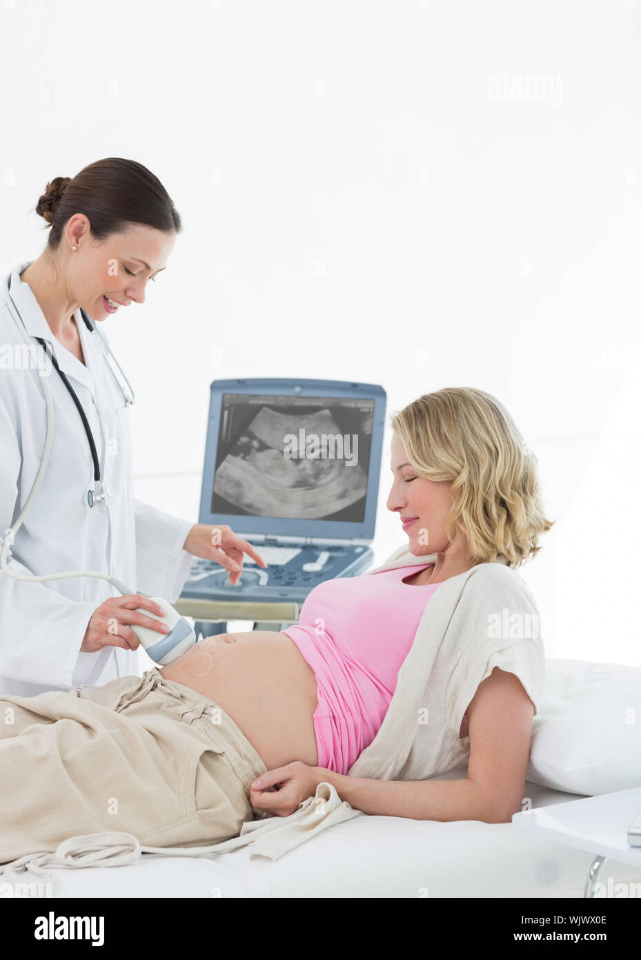female-doctor-performing-ultrasound-on-pregnant-woman-in-clinic-stock