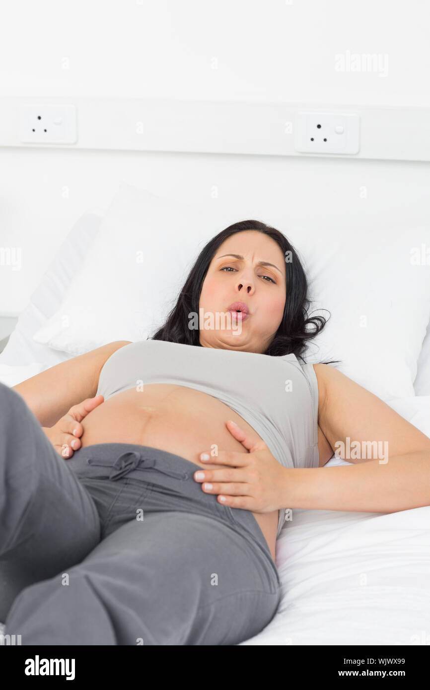 Portrait of pregnant woman suffering from labor pains lying in bed at hospital Stock Photo