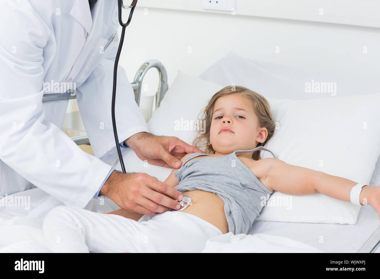 Midsection of male doctor examining stomach of sick girl in hospital
