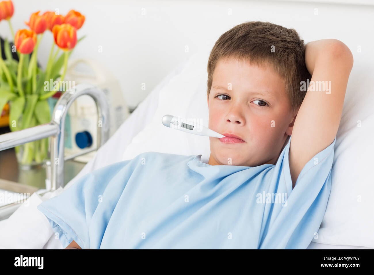 Sick boy in hospital bed with thermometer in mouth Stock Photo - Alamy