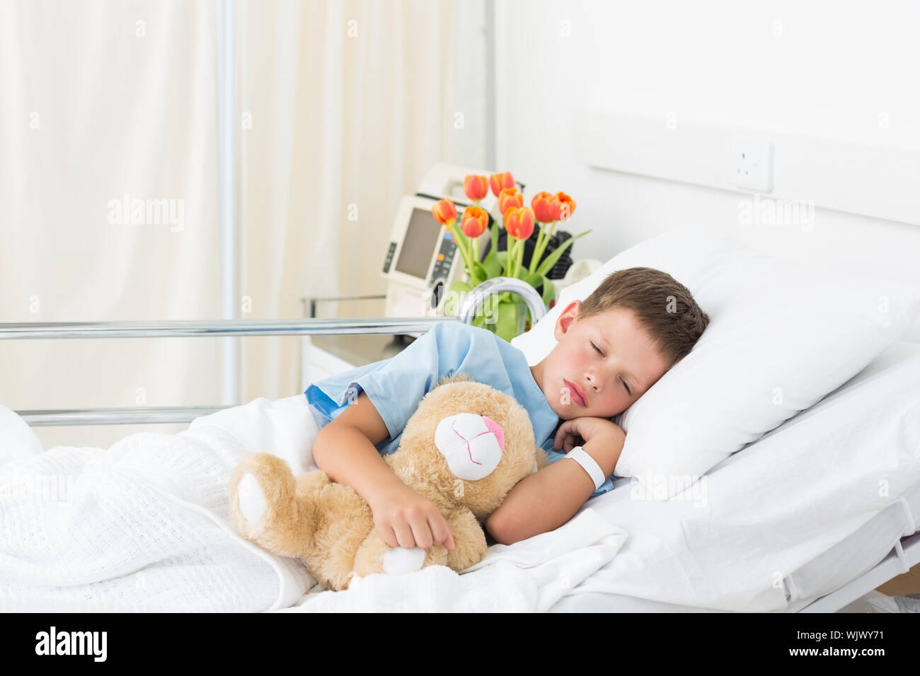 Sick little boy sleeping with teddy bear in hospital bed Stock Photo