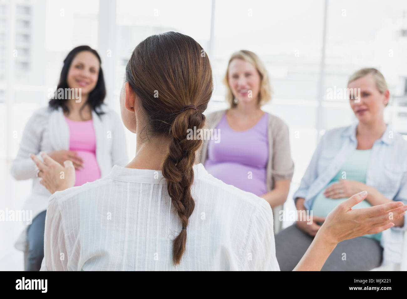 Happy Pregnant Women Listening To Gesturing Doctor At Antenatal