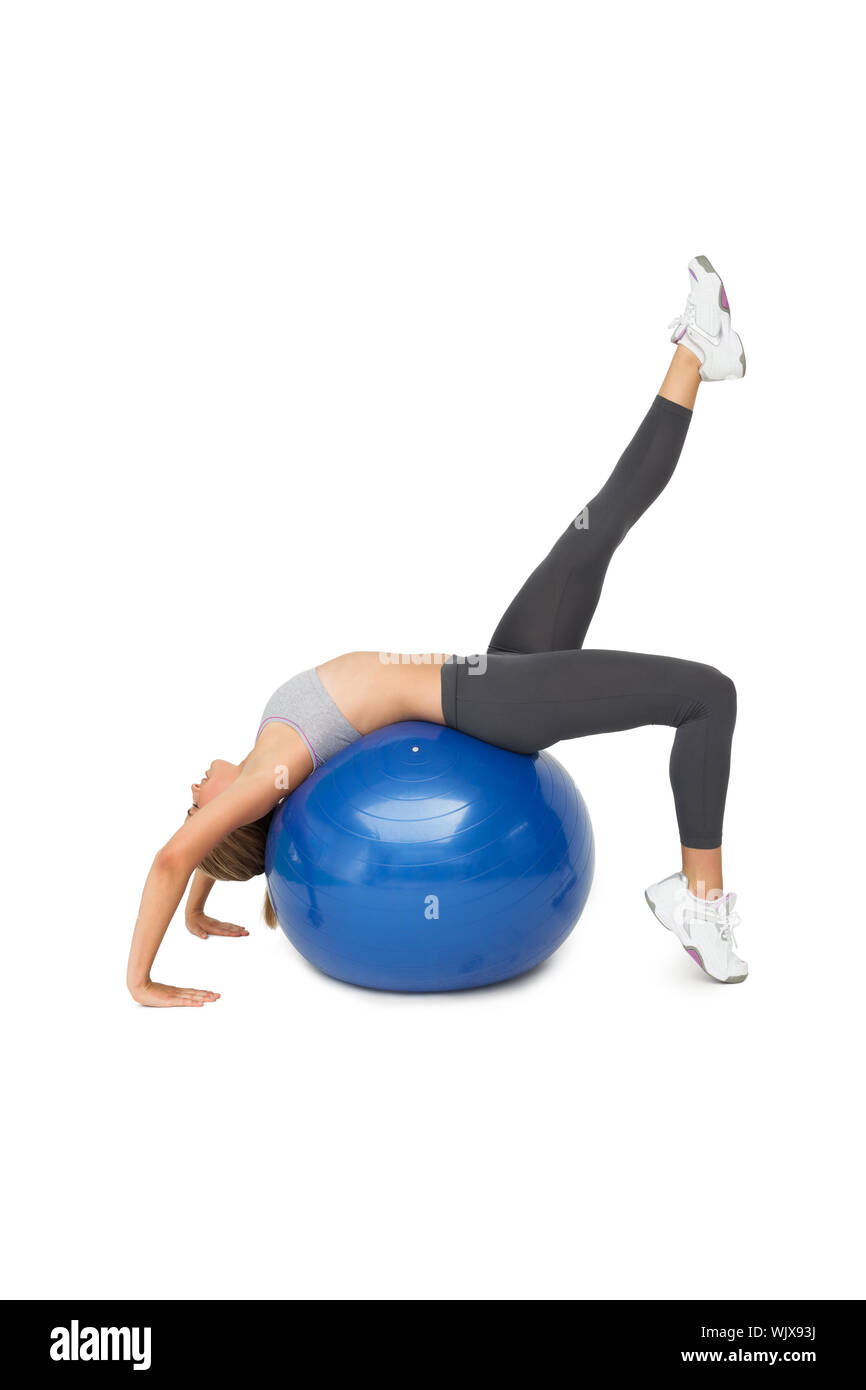 Side view of a fit young woman stretching on fitness ball over white ...
