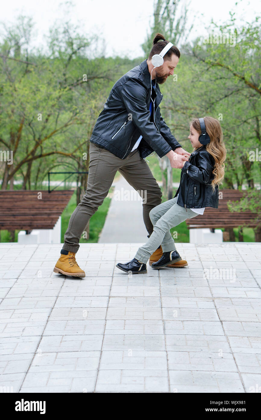 Happy little girl dances with young father in middle city street. Happy