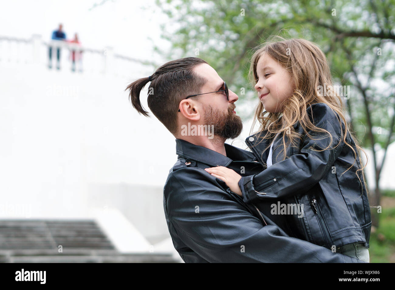 Fashionable stylish family for a walk. Daughter in the hands of dad. Happiness being a parent. Unconditional love. Time together. Family look. Urban c Stock Photo