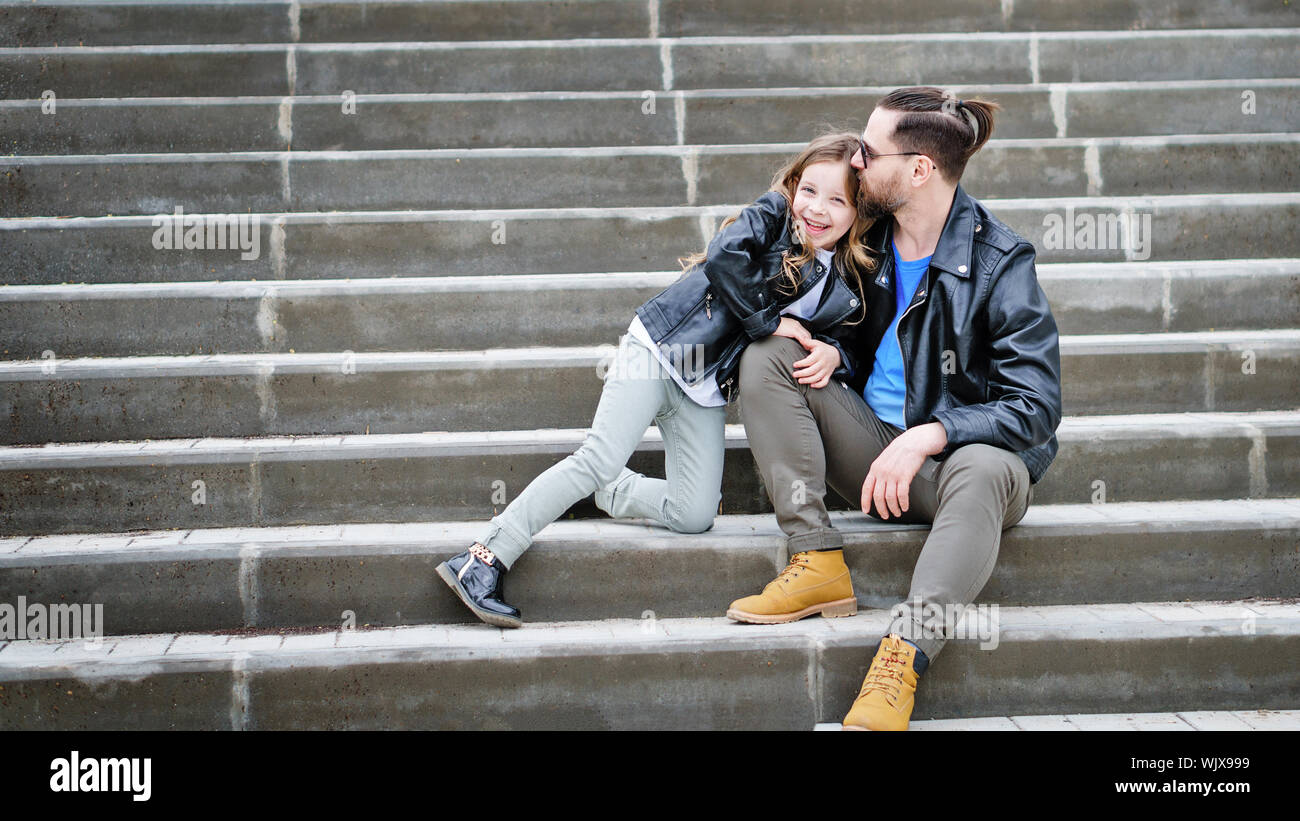 Fashionable stylish family portrait for a walk. Dad and daughter posing on the city stairs. Excursion. Travel and tourism concept. Time together. Fami Stock Photo