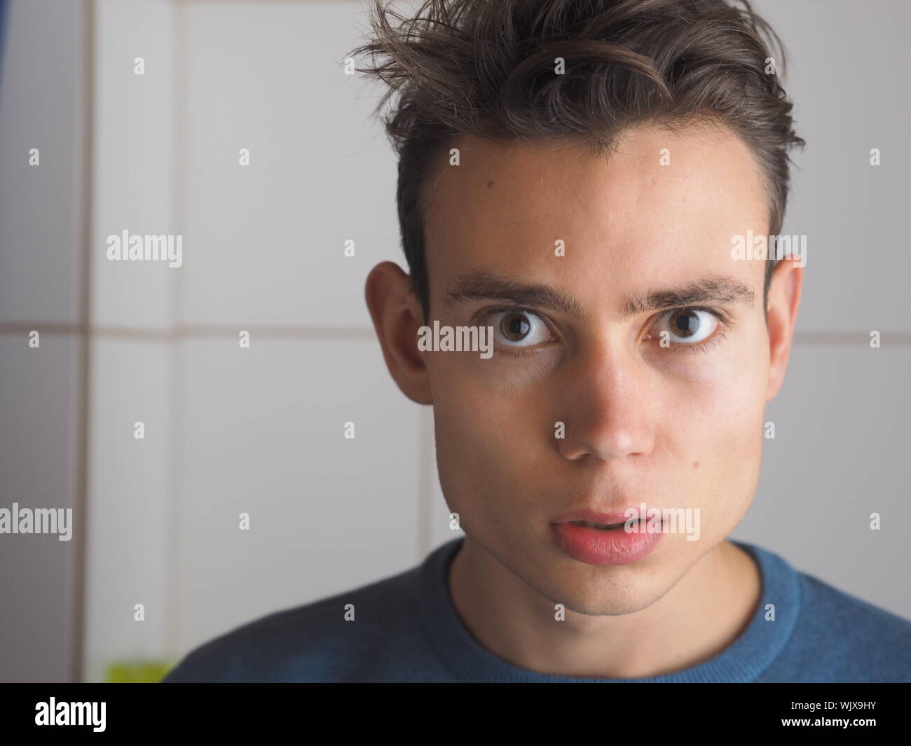 Close-up Portrait Of Shocked Young Man At Home Stock Photo