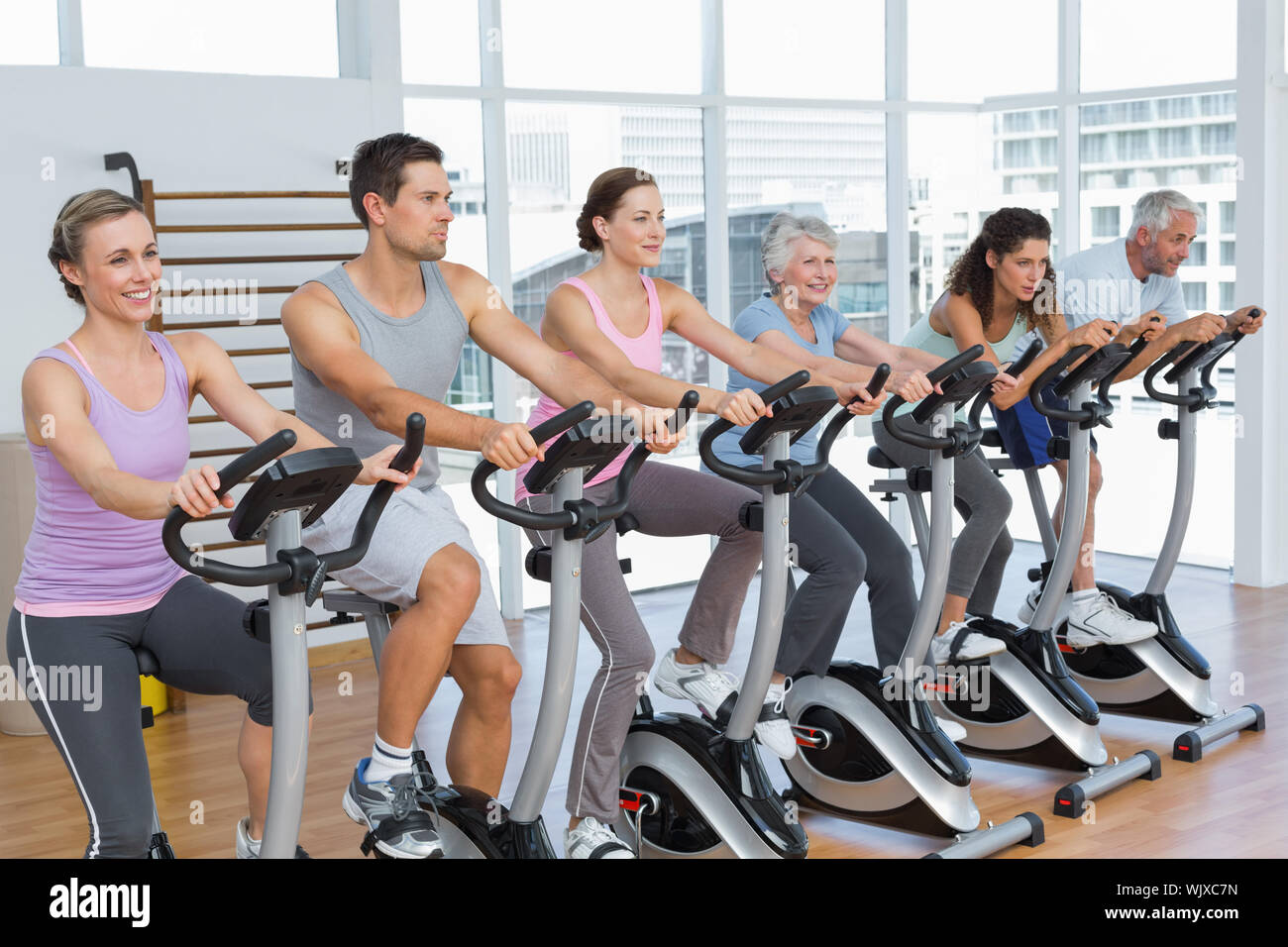 Group portrait of happy people working out at spinning class in gym ...