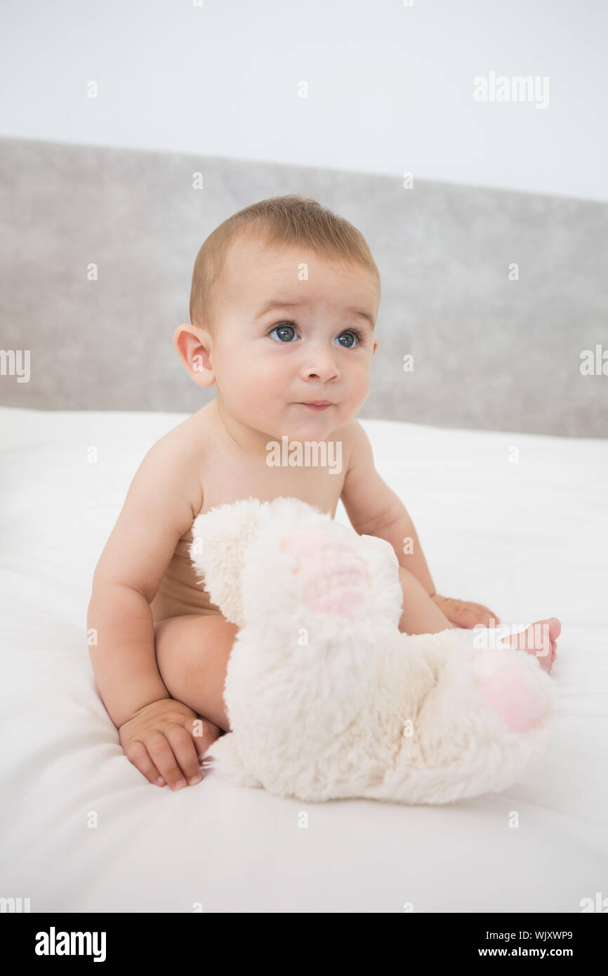 Cute baby boy with teddy bear sitting on bed Stock Photo - Alamy