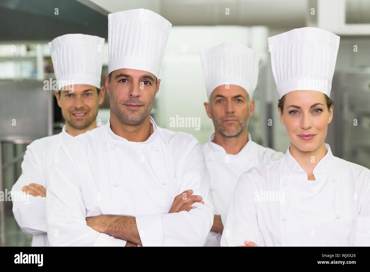 Happy team of chefs looking at the camera in a commercial kitchen Stock