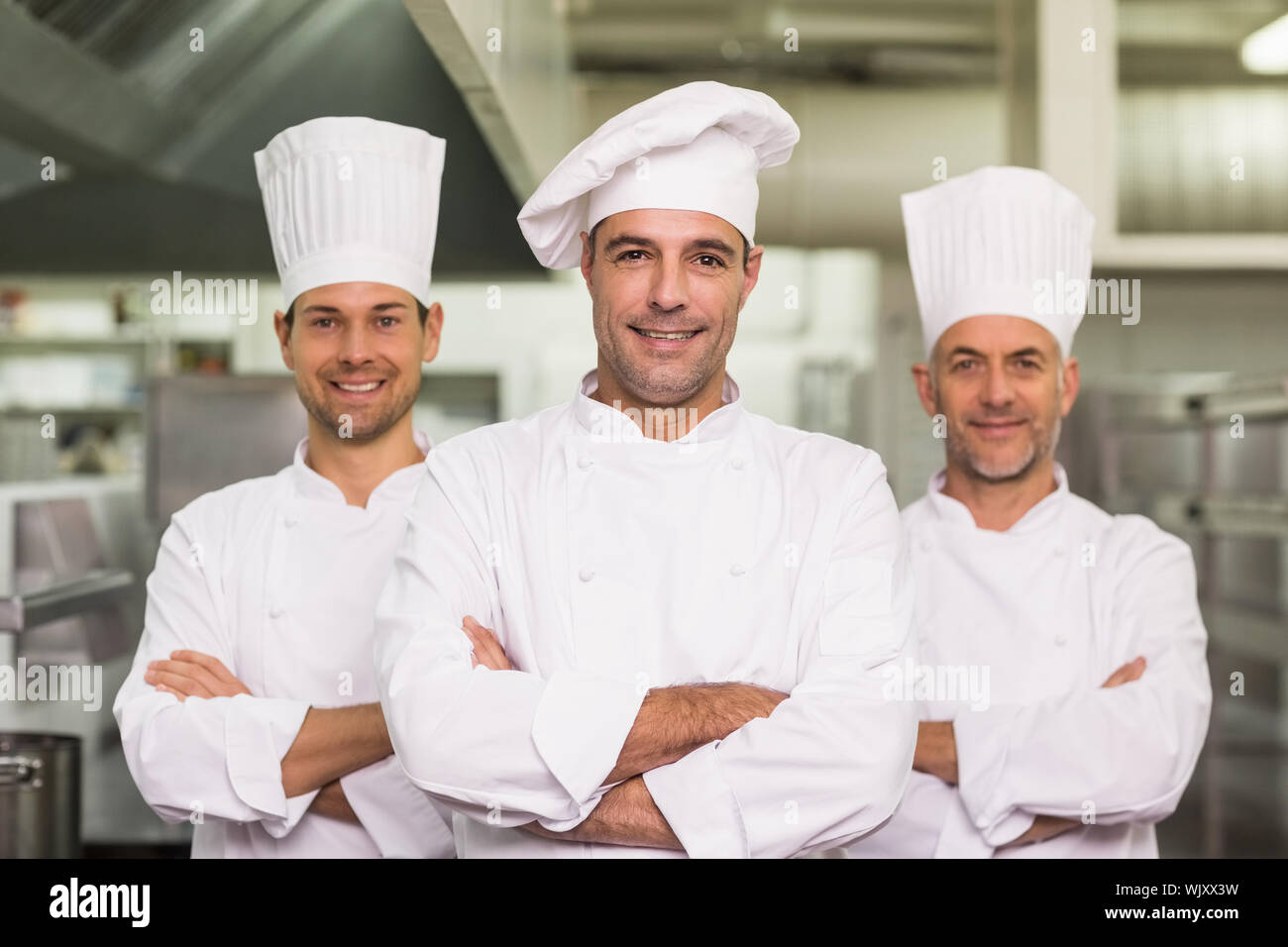 Happy team of chefs looking at the camera in a commercial kitchen Stock