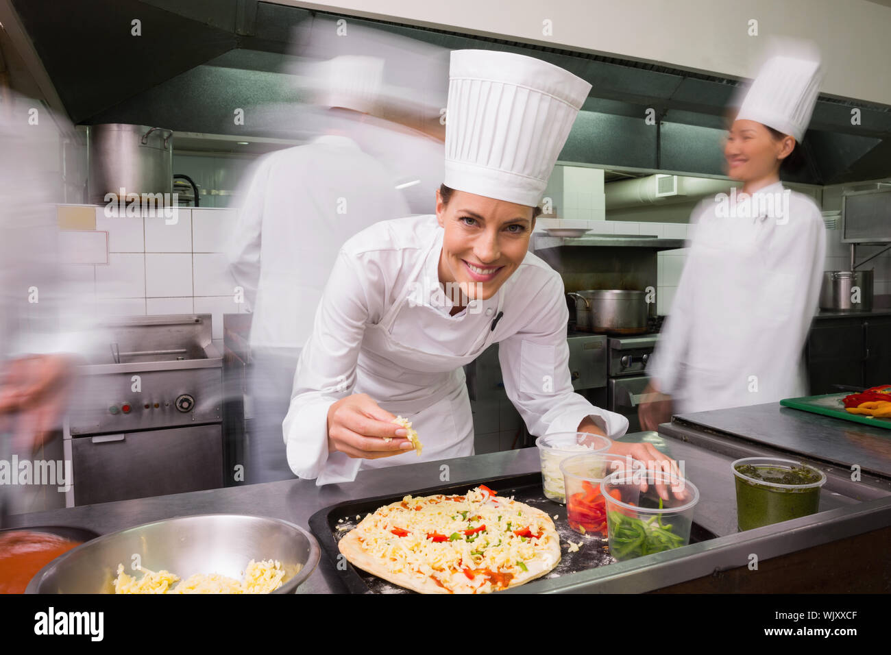 Happy chef preparing a pizza in a commercial kitchen Stock Photo