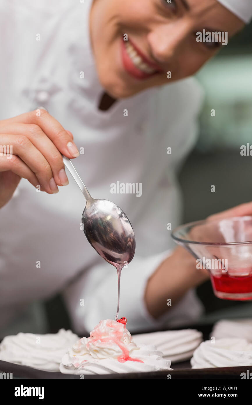 Chef pouring syrup over meringues in a commercial kitchen Stock Photo