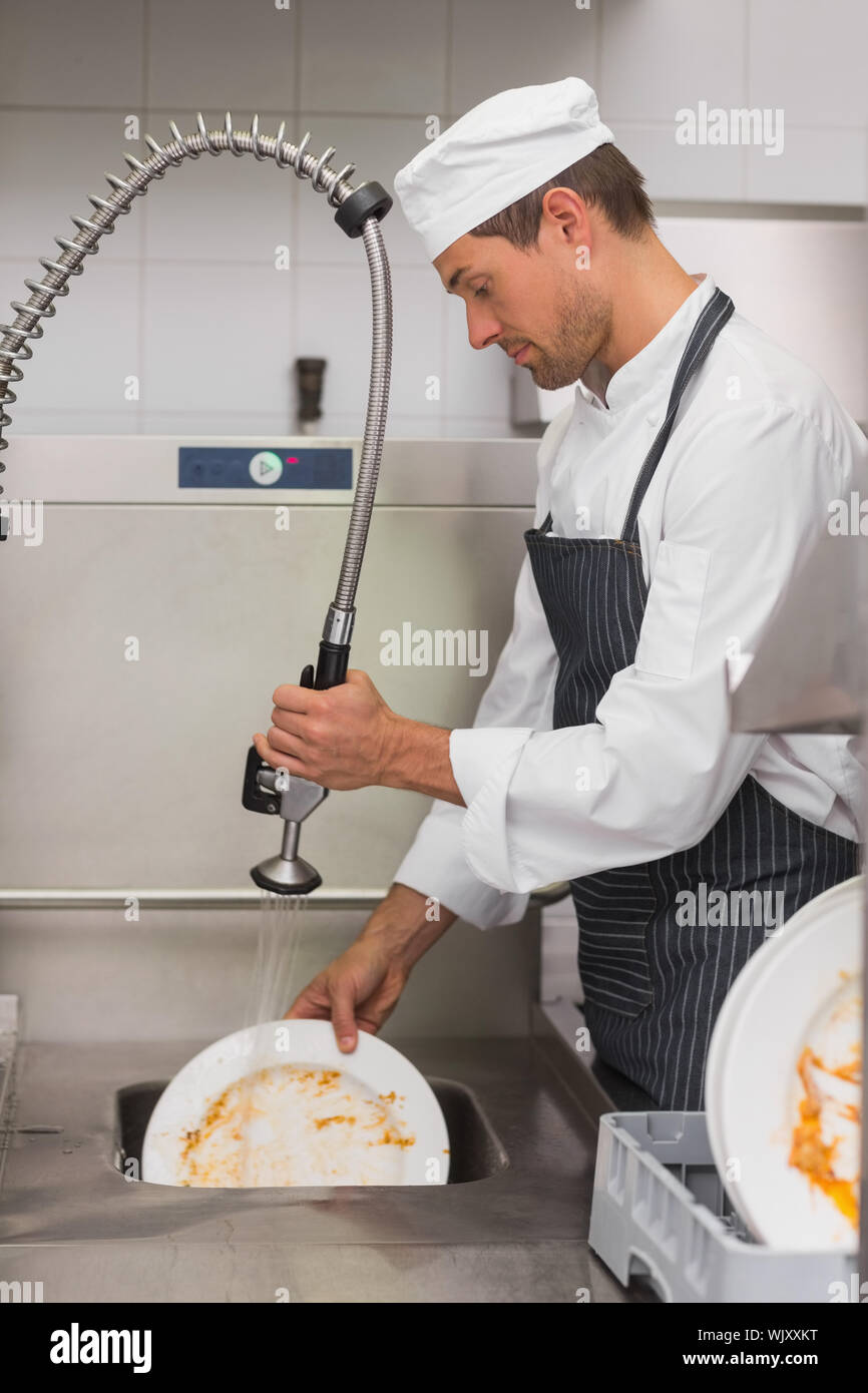 Kitchen porter cleaning plates in sink in professional kitchen Stock Photo  - Alamy