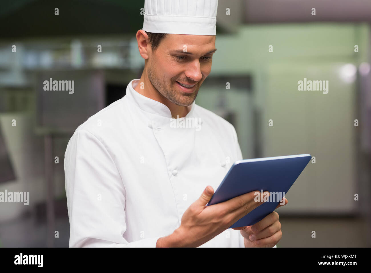 Happy chef using tablet pc in a commercial kitchen Stock Photo