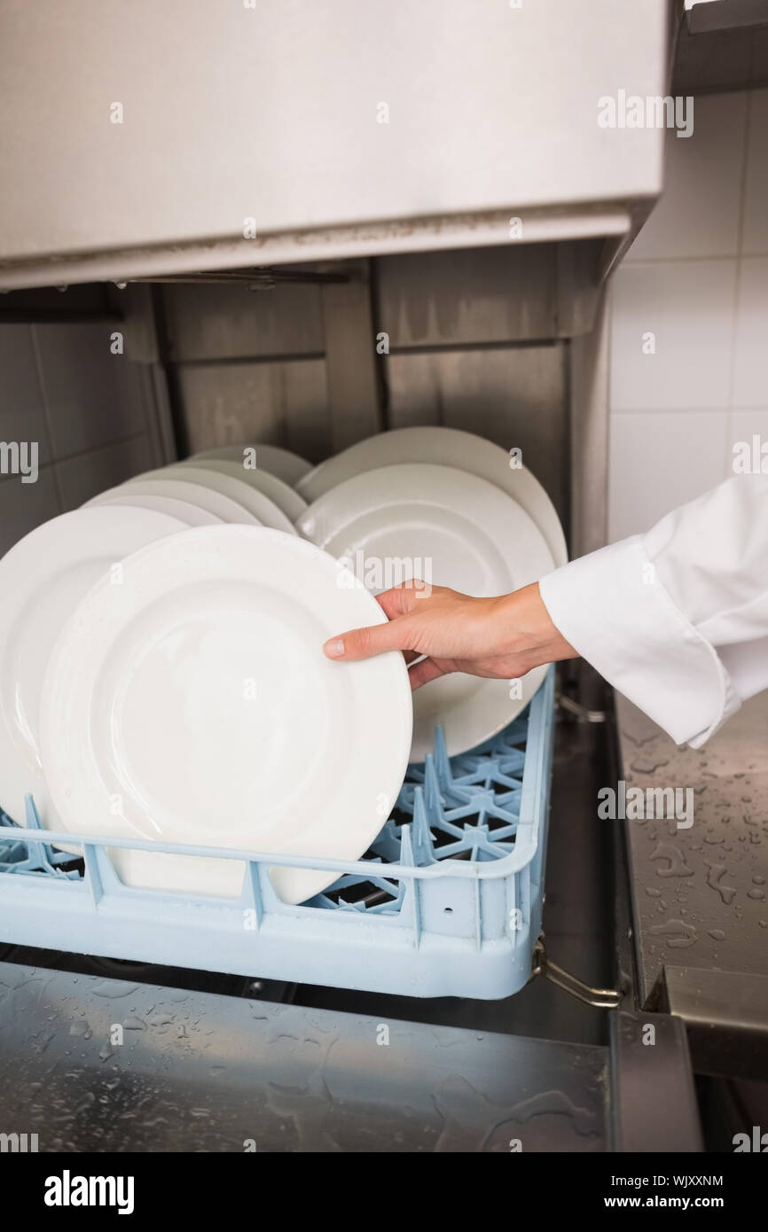Chef putting plates in drying rack in a commercial kitchen Stock Photo -  Alamy