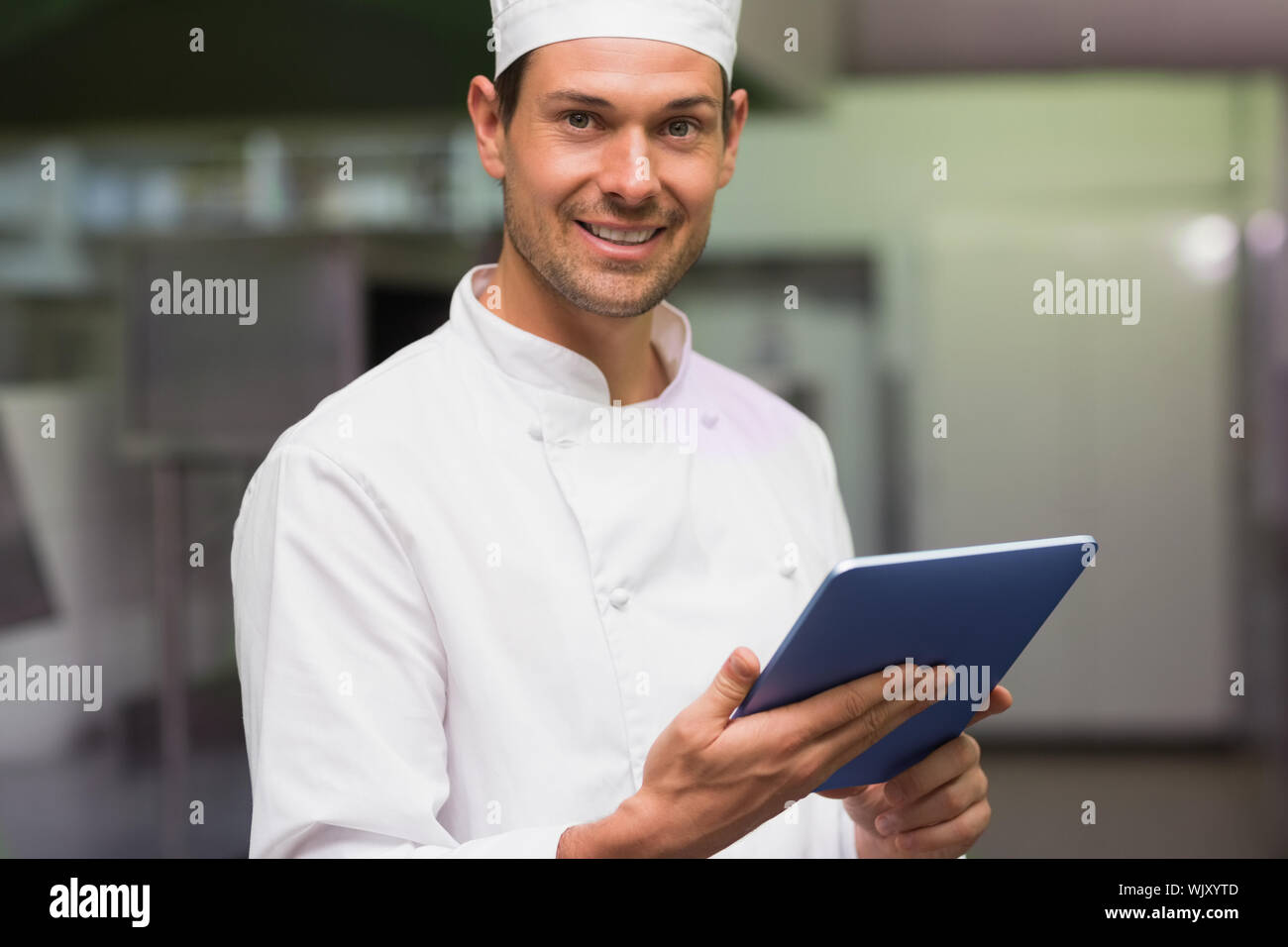 Happy chef using tablet pc in a commercial kitchen Stock Photo