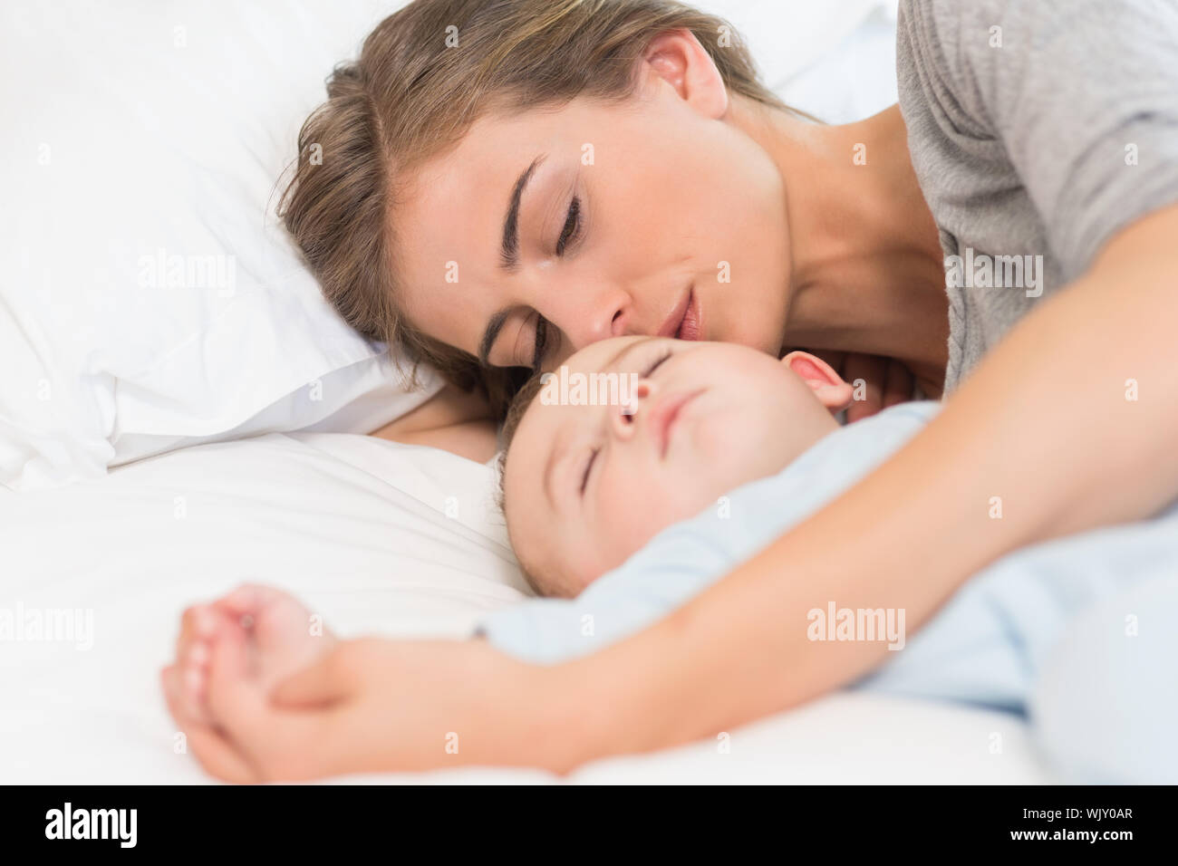 Mother sleeping with baby son on bed at home in bedroom Stock Photo Alamy