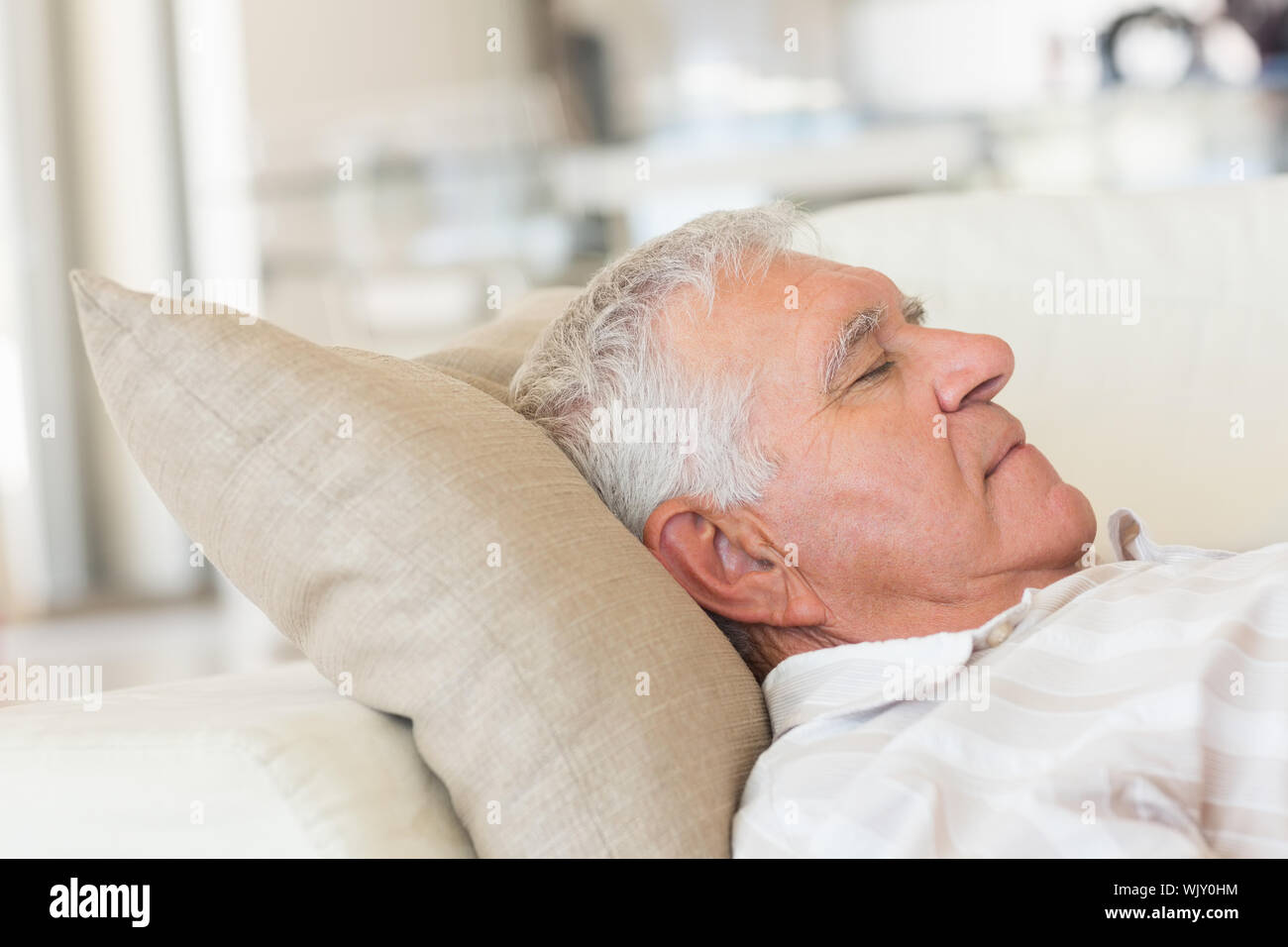 Senior man sleeping on the couch at home in the living room Stock Photo ...
