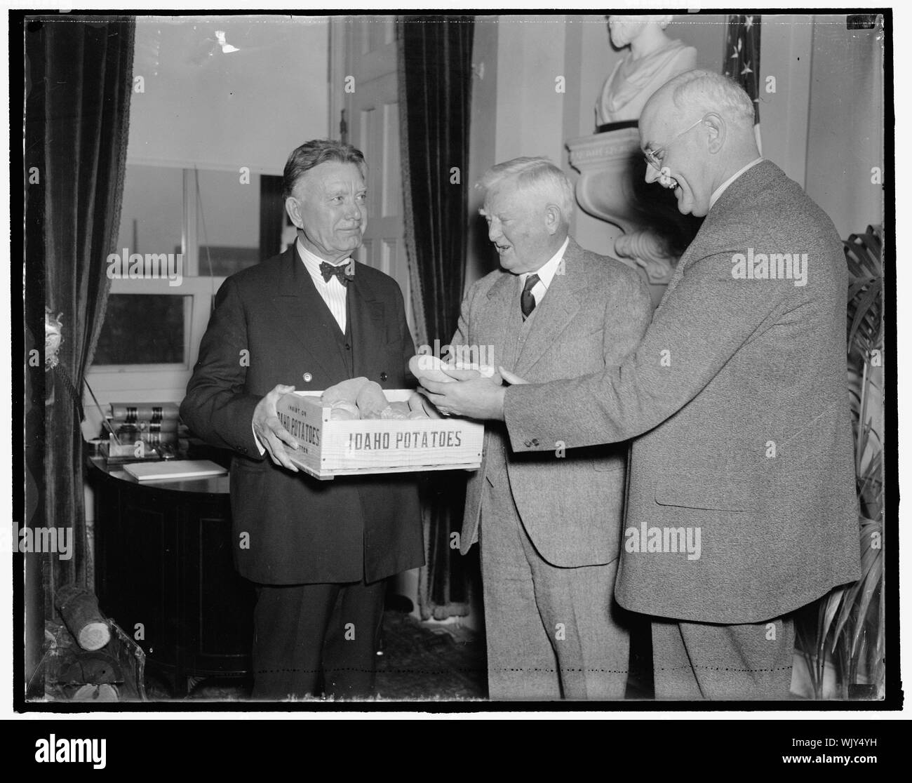 Idaho spuds presented to vice president. Washington, D.C., Dec. 6. A box of Idaho's choicest potatoes were presented today to Vice President John N. Garnger by Senators William E. Borah, (left) and James P. Pope, both from the famous potato-growing state. The presentation was the signal for challenge issued by the Maine Congressional Delegation to the Idaho Solons for a potato eating contest which will be staged in the House Restaurant tomorrow to test the relative merits of the spuds from the two states. 12/6/37 Stock Photo