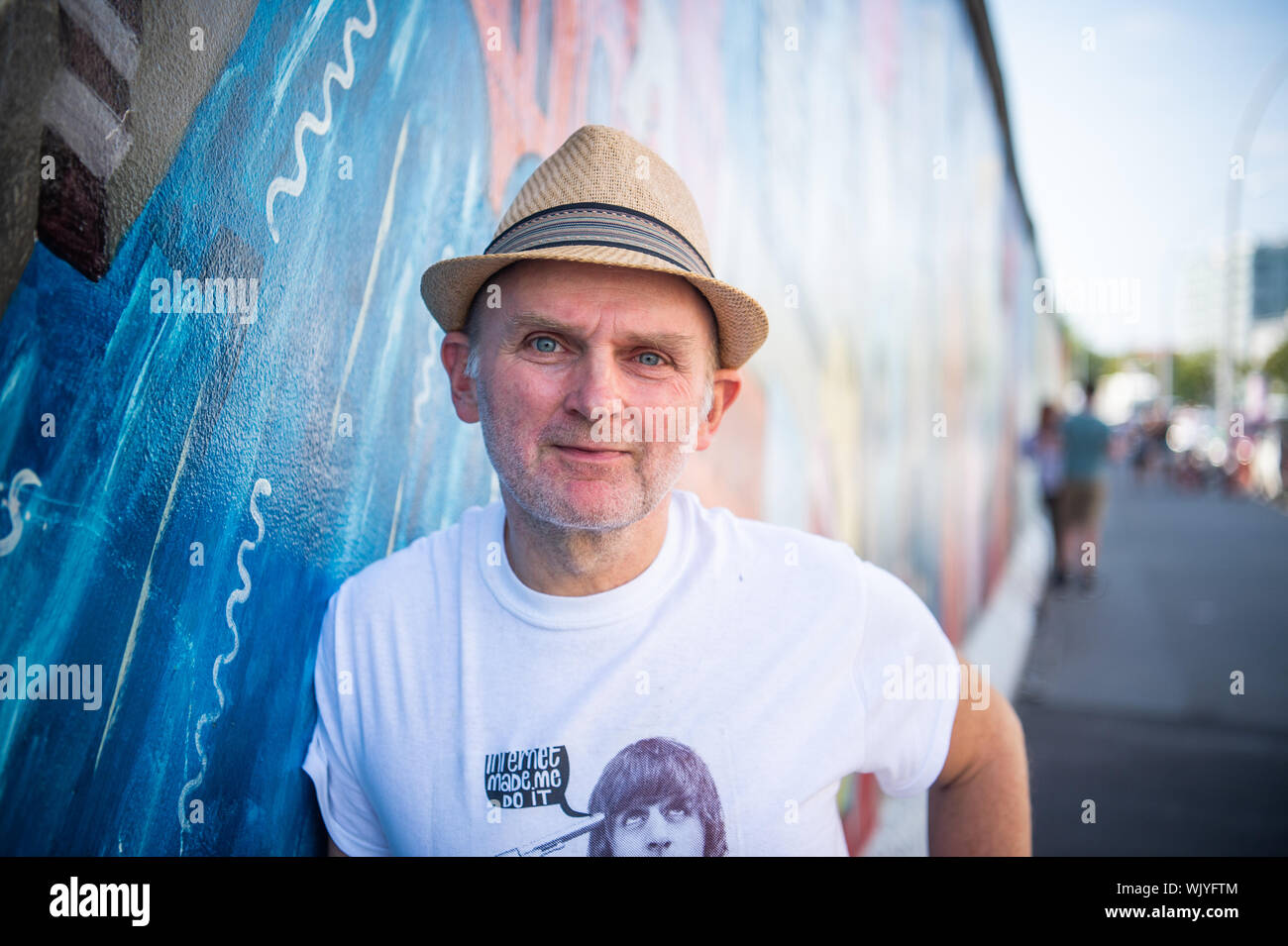 Berlin, Germany. 22nd Aug, 2019. Jim Avignon, artist, stands in front of his work at the East Side Gallery. Almost 30 years ago, artists immortalized themselves here and reinterpreted the longest remaining section of the Berlin Wall with their works of art. (for 'Wall Artist Avignon: East Side Gallery awarded anew each year') Credit: Arne Immanuel Bänsch/dpa/Alamy Live News Stock Photo