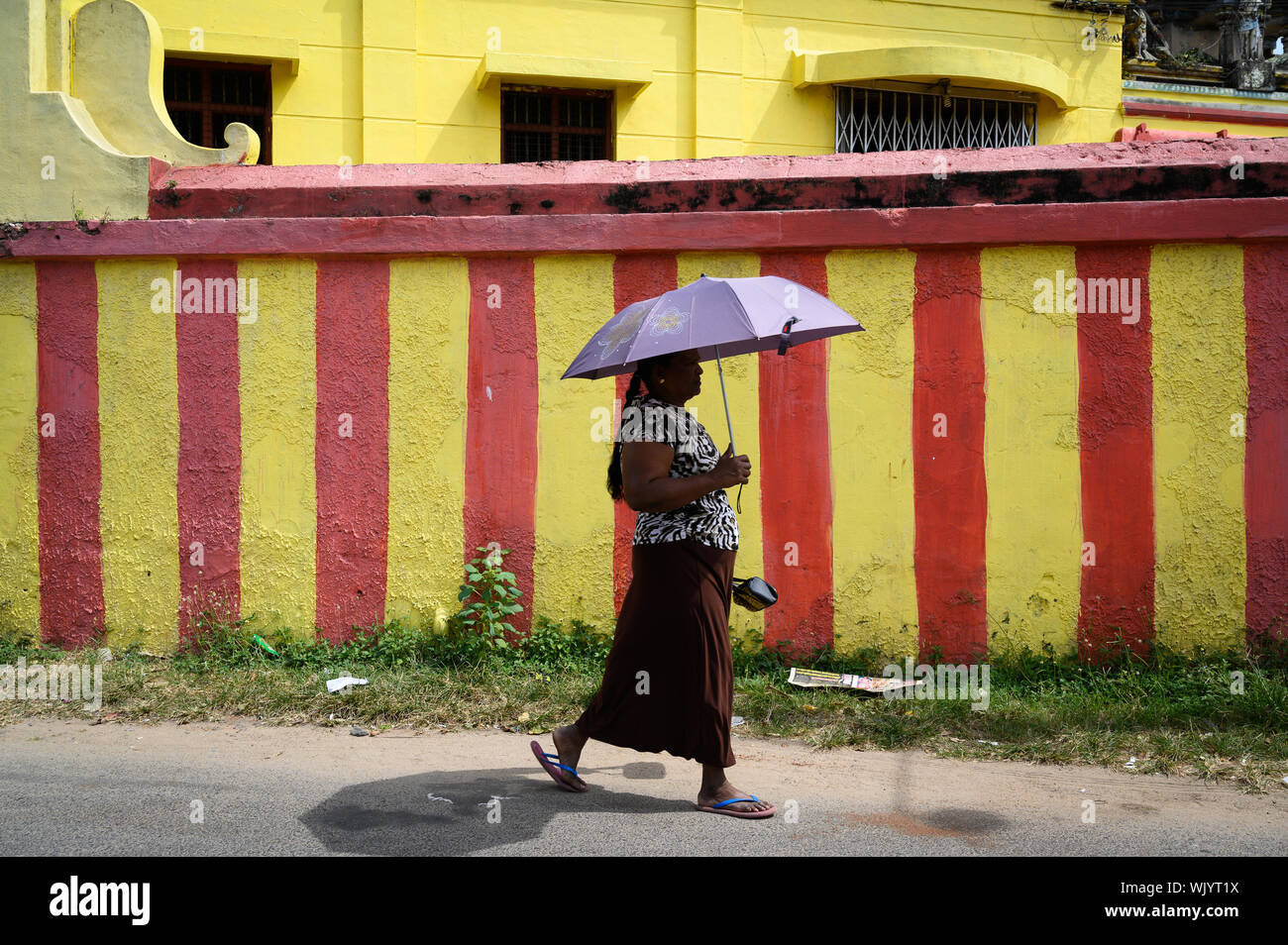 Woman with an umbrella walking down the street in Negombo, Sri Lanka Stock Photo