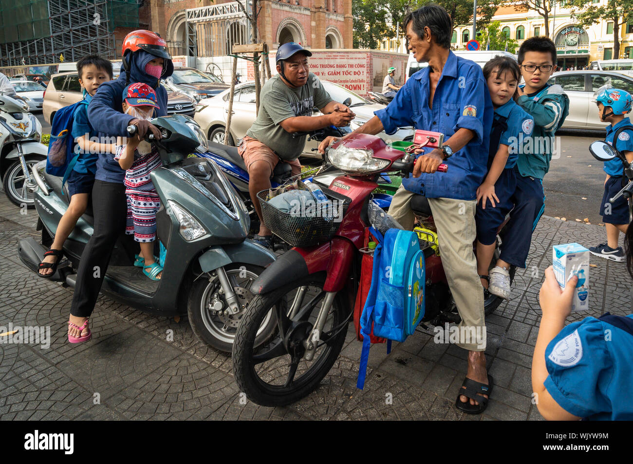 Parents on their motor scooters picking up their kids from school, Ho Chi Minh City, Vietnam Stock Photo