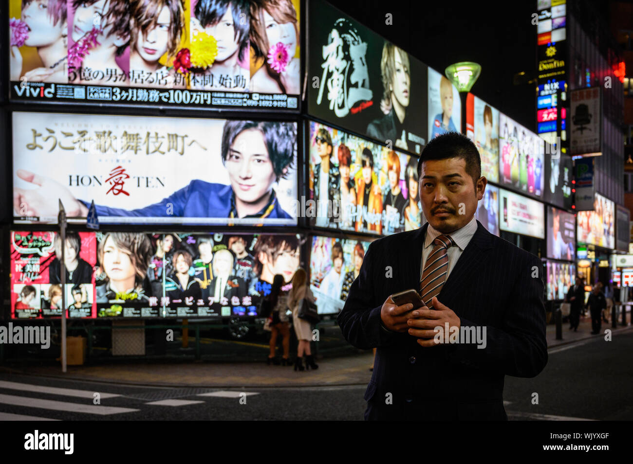 Well-tailored Japanese man against the neon lights, Shinjuku, Tokyo, Japan Stock Photo