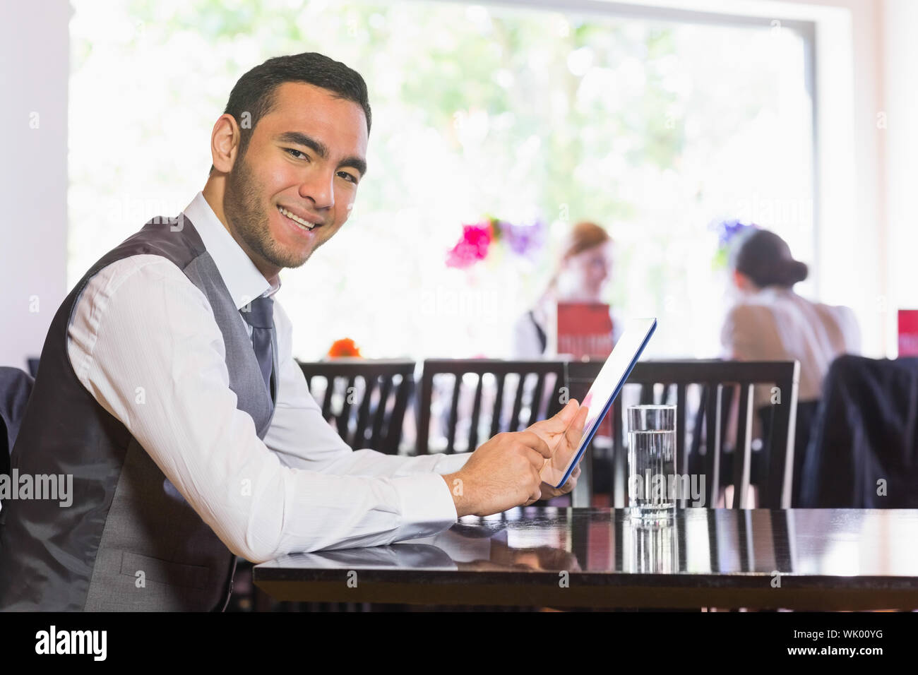 Happy businessman using tablet and smiling at camera Stock Photo