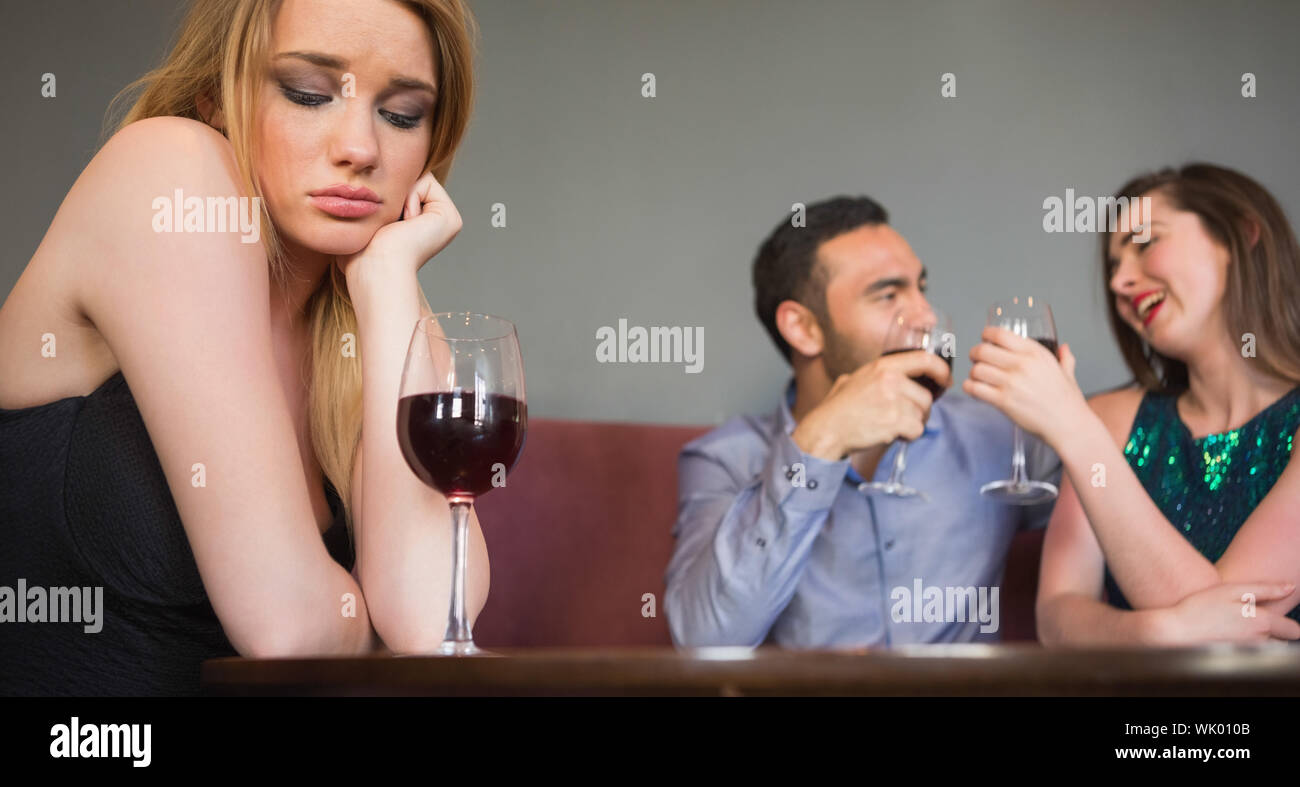 Blonde woman feeling envious of two people are flirting beside her Stock Photo