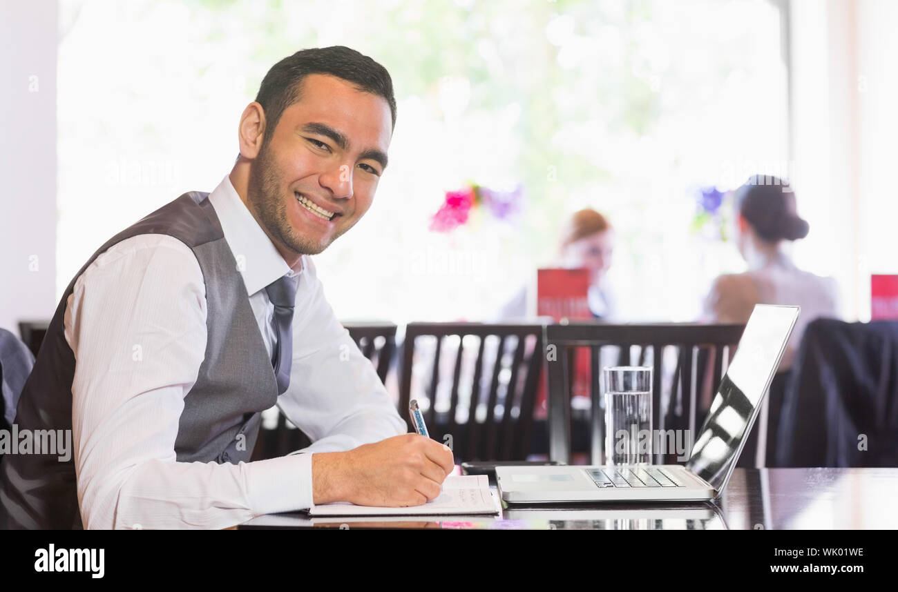 Smiling businessman writing while looking at camera Stock Photo