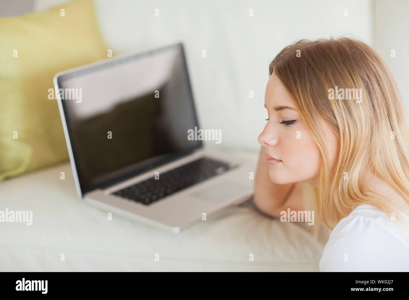 Thoughtful woman sitting on floor in front of laptop Stock Photo - Alamy