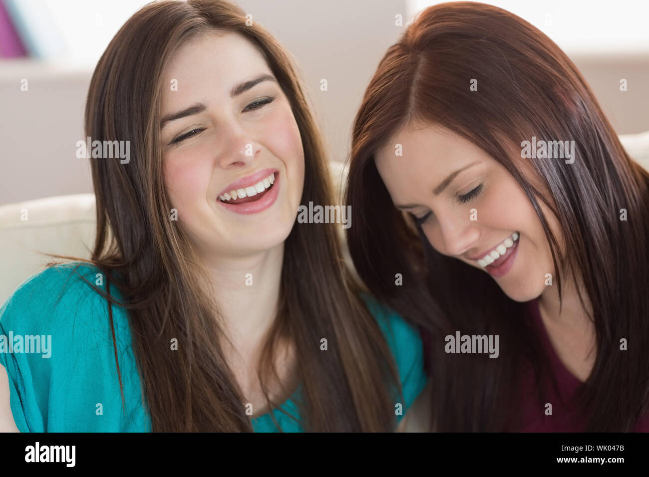 Two laughing friends sitting on the couch Stock Photo
