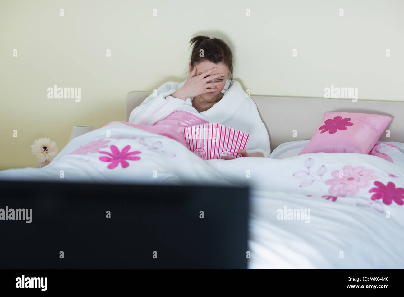 Pretty teen wearing bathrobe watching scary movie Stock Photo