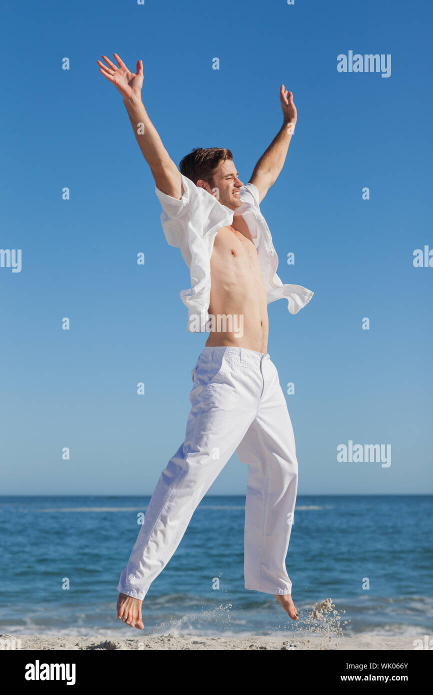 Attractive man jumping on beach Stock Photo
