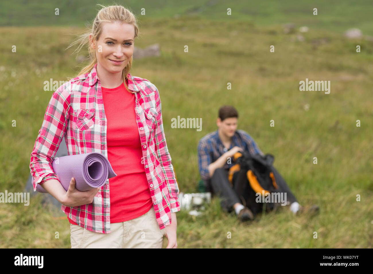 Happy woman carrying camping mat Stock Photo Alamy