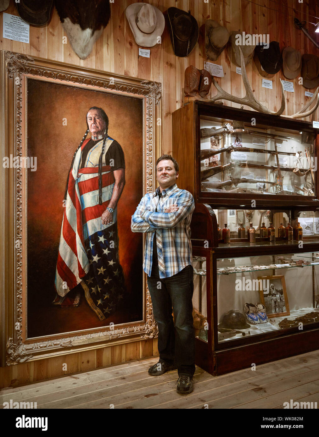 In his studio and art gallery in tiny Hulett, Wyoming, celebrated western artist Bob Coronato stands beside his most famous and controversial painting, of American Indian activist Russell Means Stock Photo