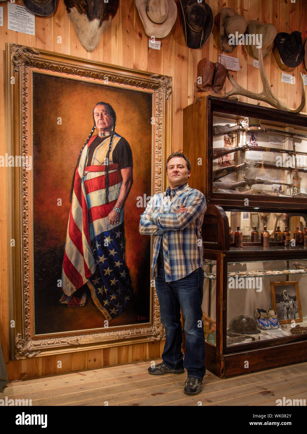 In his studio and art gallery in tiny Hulett, Wyoming, celebrated western artist Bob Coronato stands beside his most famous and controversial painting, of American Indian activist Russell Means Stock Photo