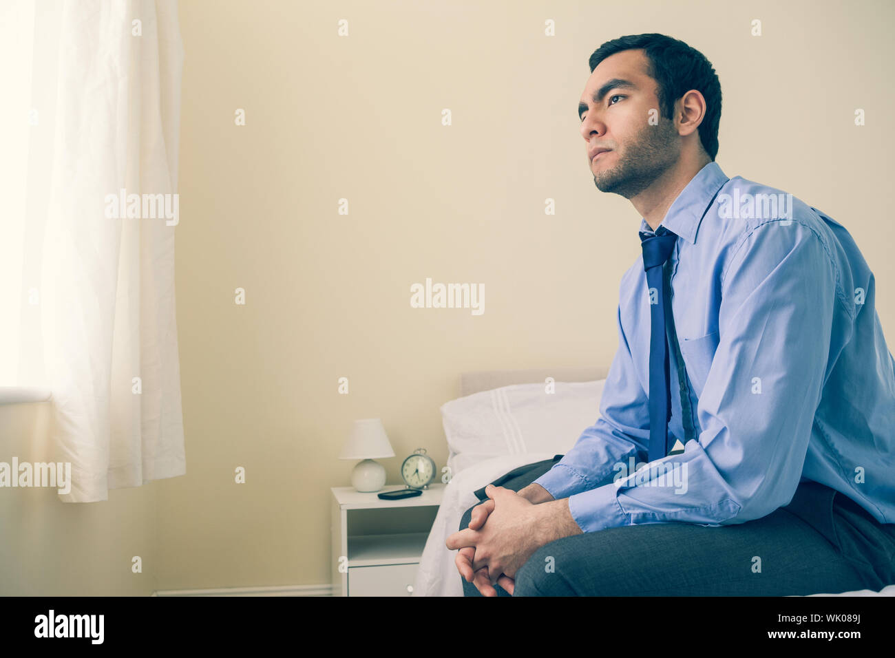 Thinking man looking away sitting on his bed Stock Photo