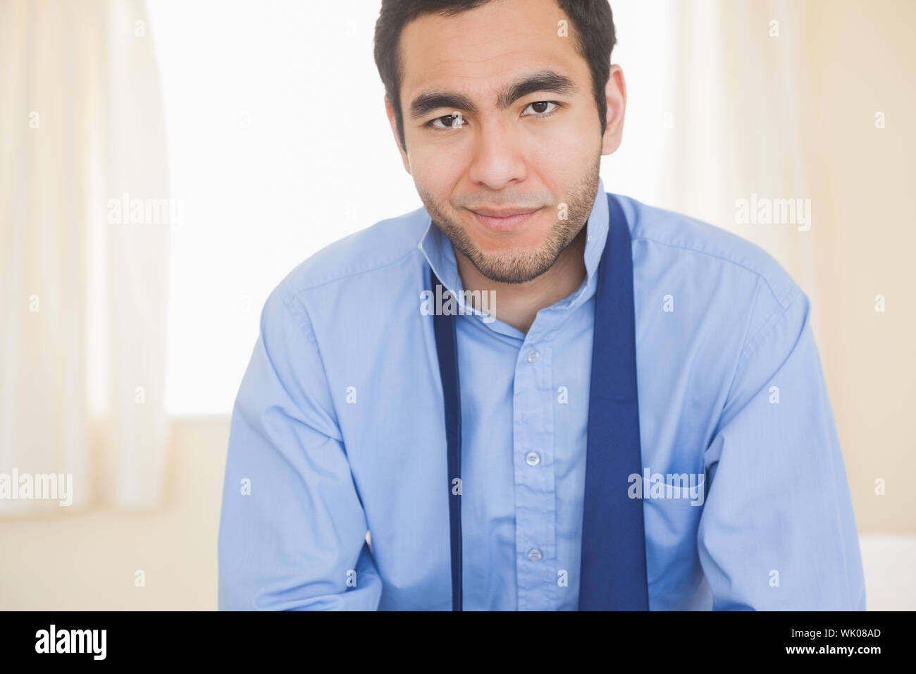 Relaxed man smiling at camera sitting on a bed Stock Photo