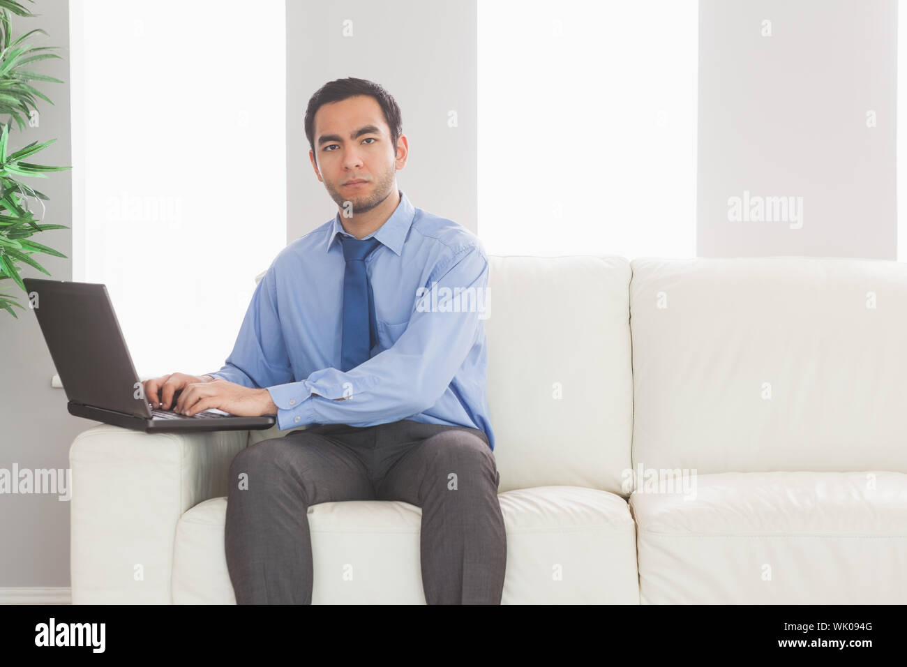Stern businessman using his laptop while sitting on cosy sofa Stock ...